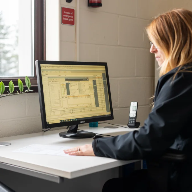 Mobad staff member sitting in front of PC using cutting edge job management software