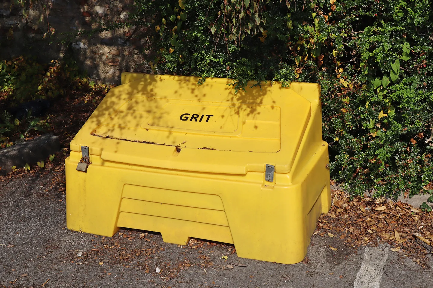 Roadside grit bin sat amongst shrubs